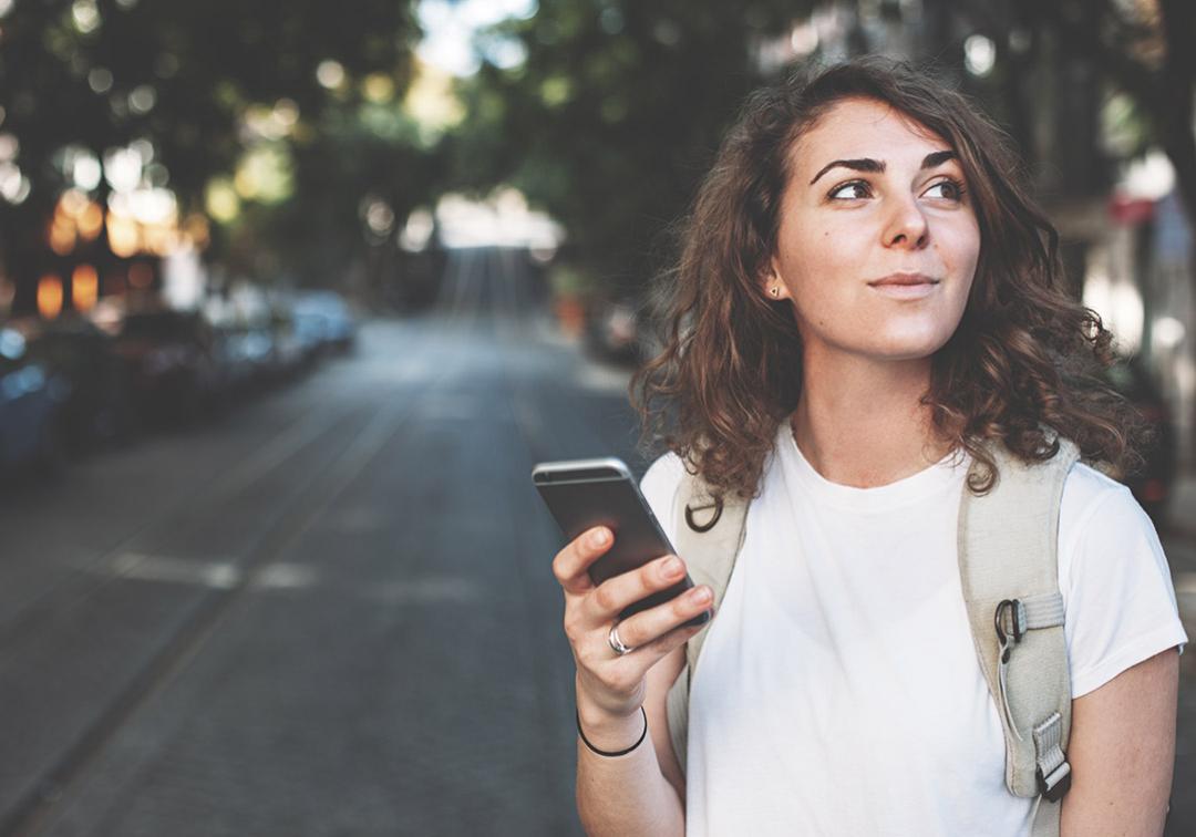 Girl walking in suburban area holding phone
