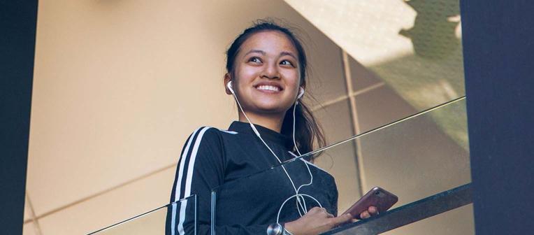 Woman walking up stairs, with headphones in ears.