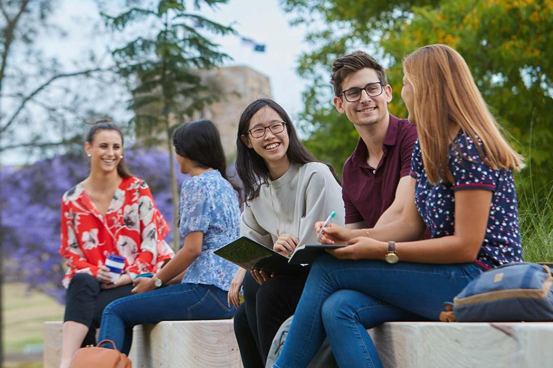 Students sitting on a bench outside at St Lucia campus